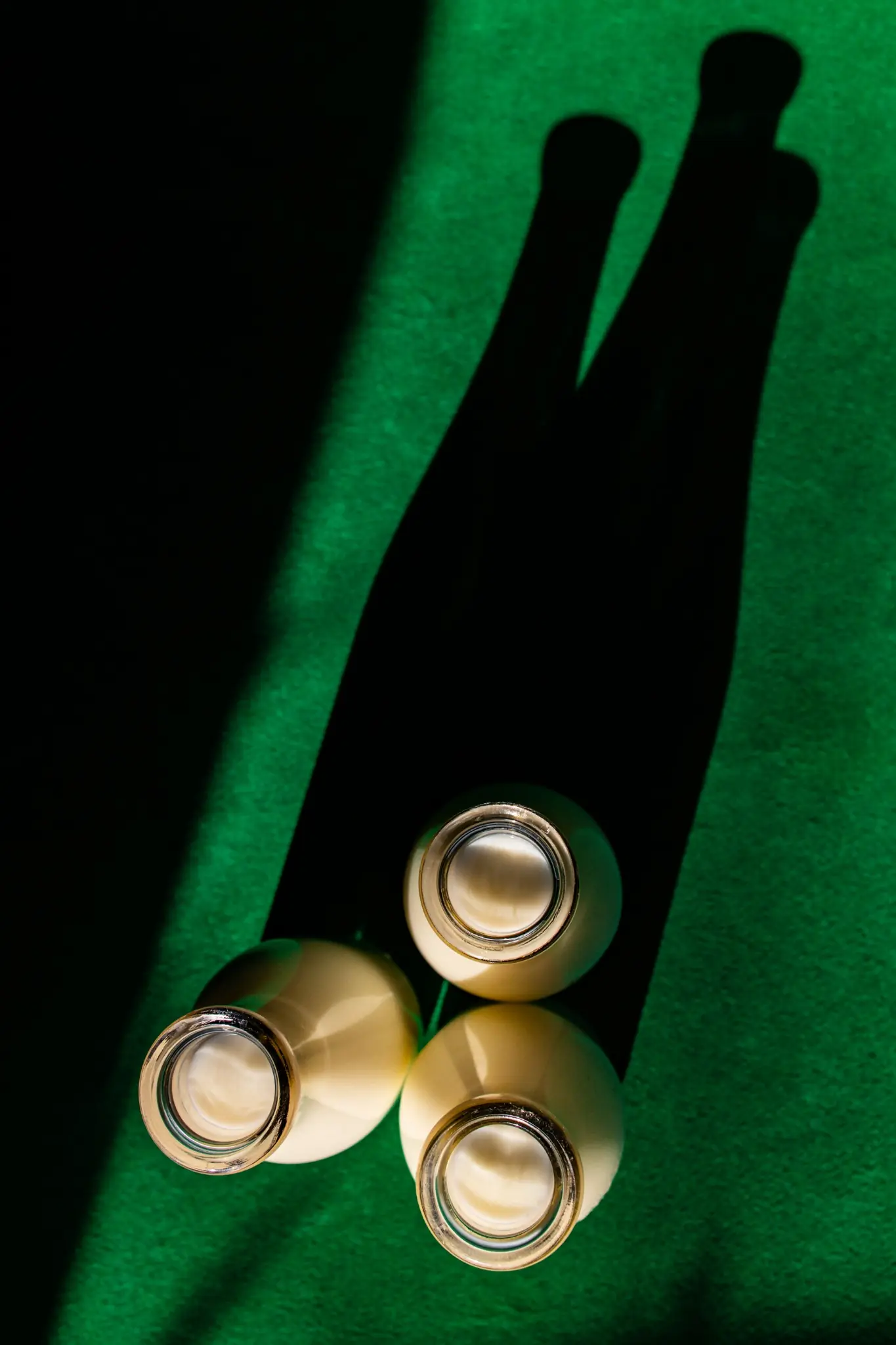Milk bottles casting long shadows on a green surface