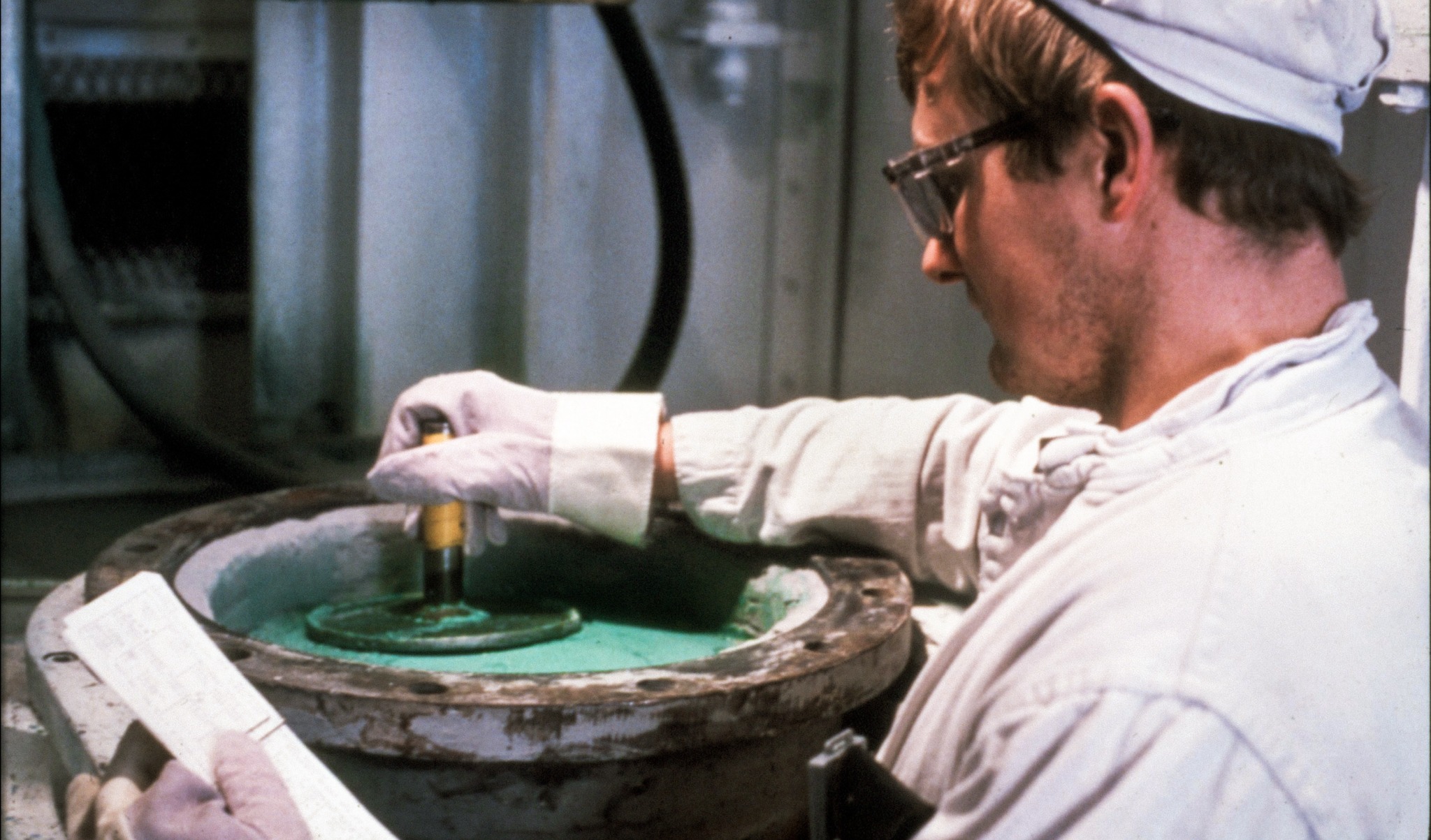 Worker handling green uranium tetrafluoride powder at a processing facility