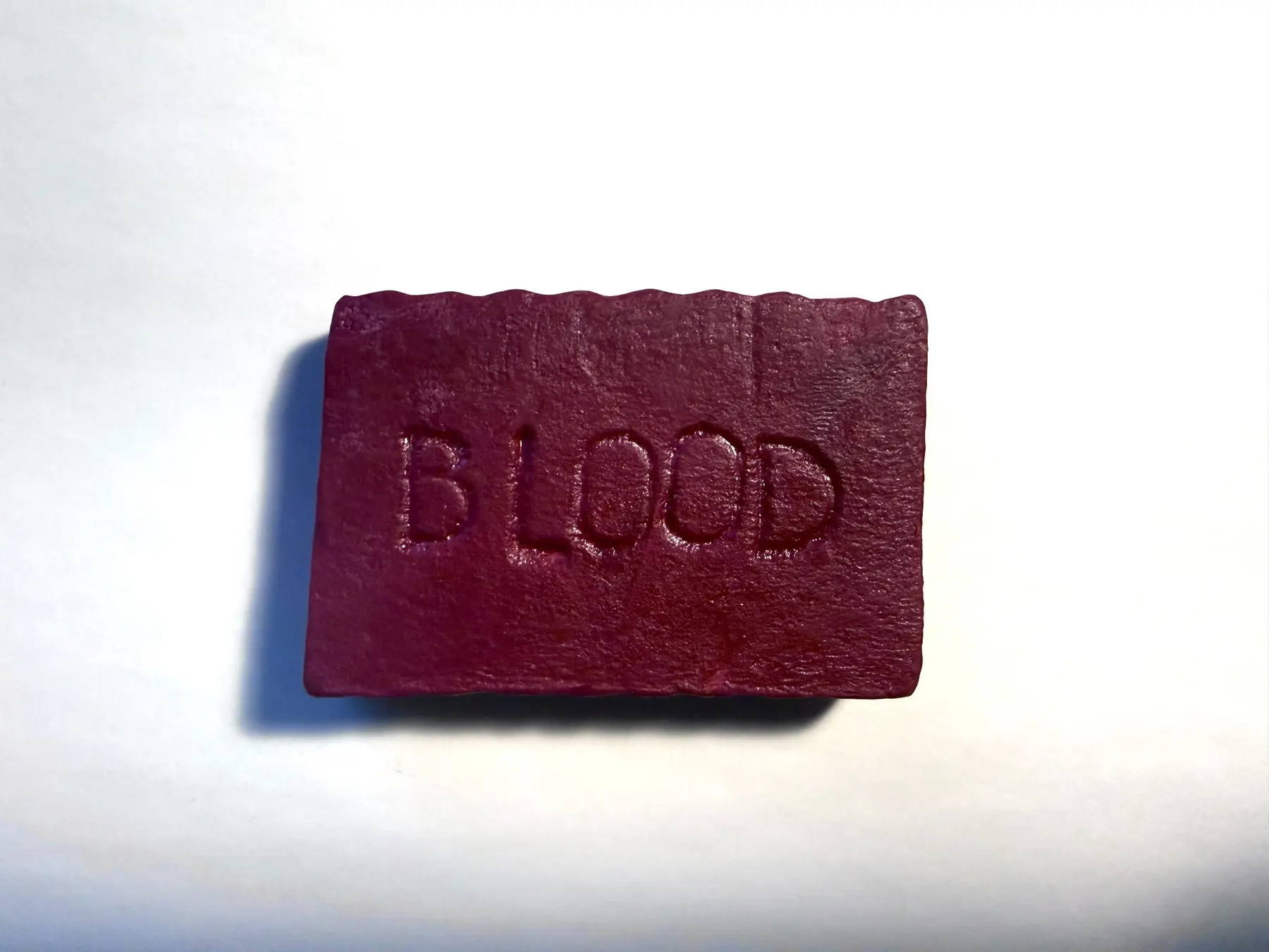 A handmade dark-red bar of goat’s milk soap embossed with the word BLOOD