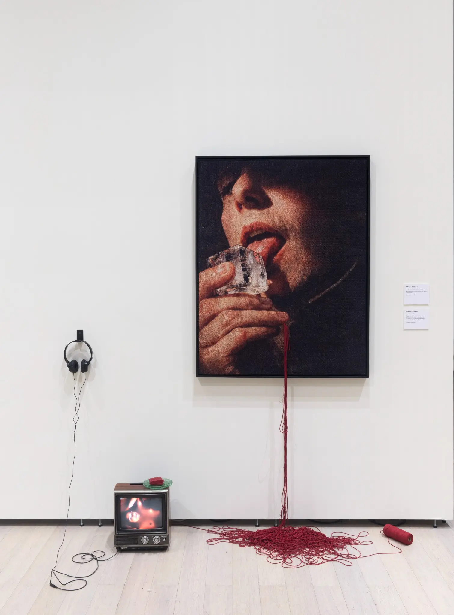 Installation view with Self-Portrait of Queer Latina Licking ICE, a CRT television playing Blood Bath, red soap, red thread and headphones